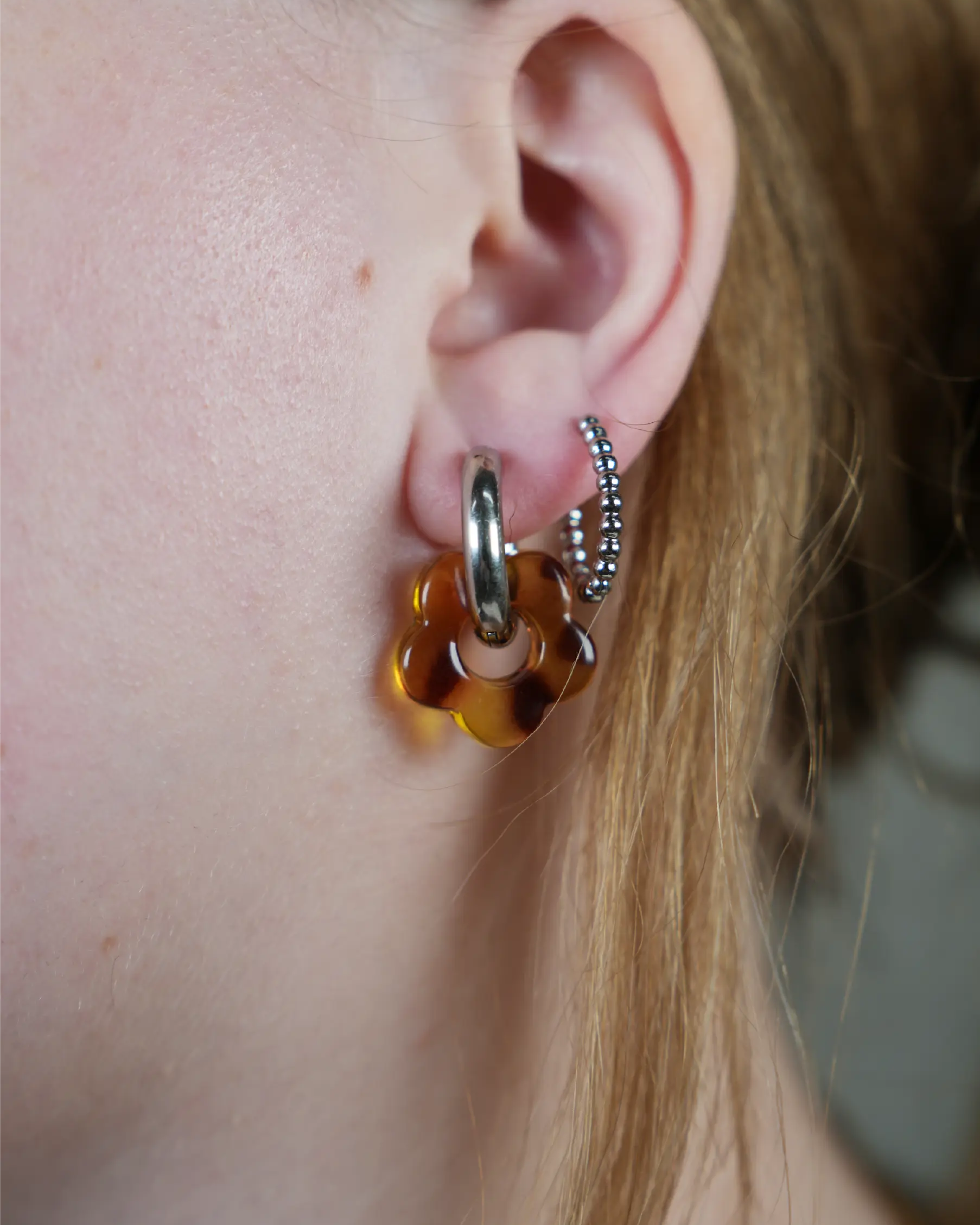 Oorbel in het zilverkleurig met een bloemetje in het bruin met vlekken